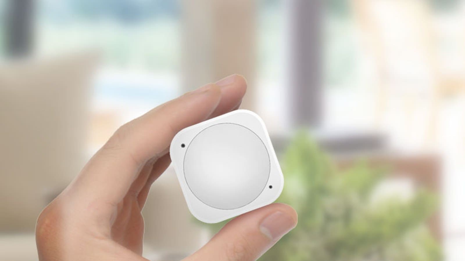 Aeotec MultiSensor 6 Z-Wave sensor held in a hand in a living room
