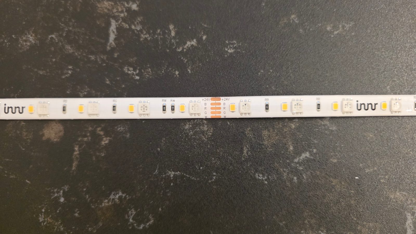 Close-up of the Innr FL 250 C strip showing RGBW solder pads and marked cut points
